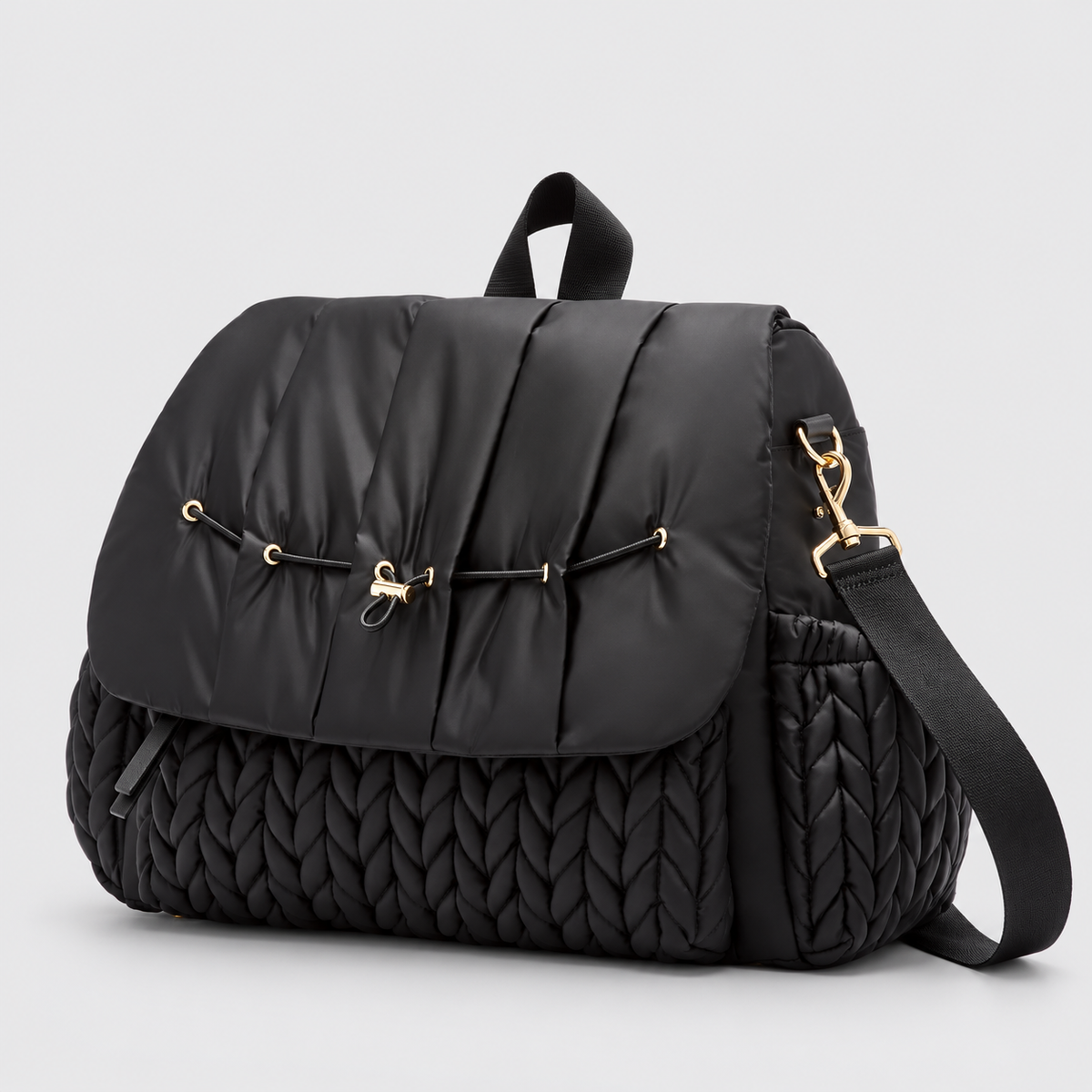 NAEVII Elara Diaper Bag Backpack in black, three-quarter side view with quilted flap, gold-tone drawstring clasp and detachable shoulder strap#Color_Black