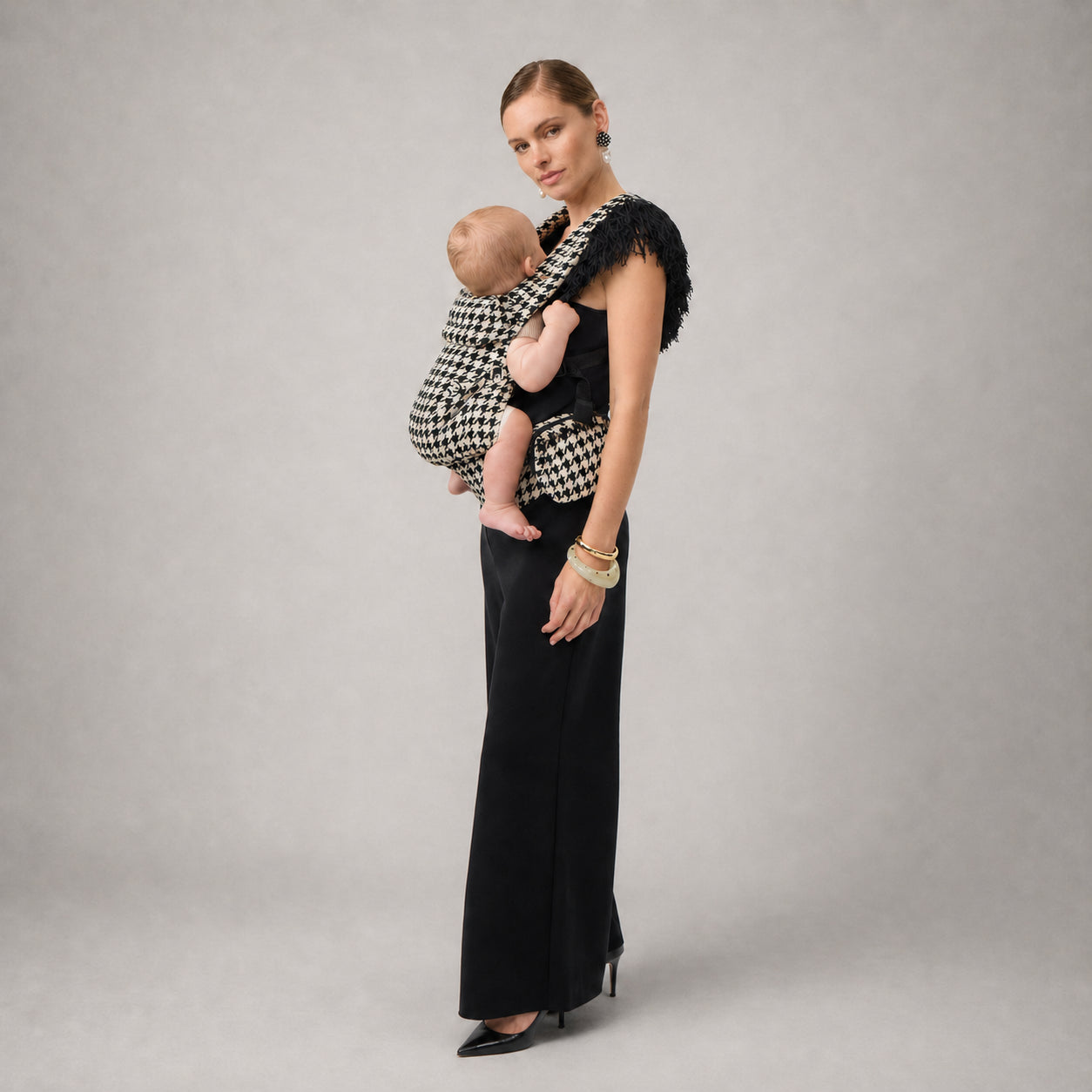 Woman carrying baby on the hip in NAEVII Limitless Baby Carrier, black and white Houndstooth#Color_Houndstooth