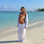 Woman on the beach carrying newborn in NAEVII Soft Baby Carrier, terracotta Brown#Color_Brown