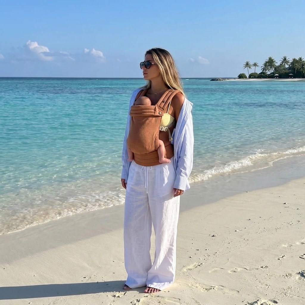 Woman on the beach carrying newborn in NAEVII Soft Baby Carrier, terracotta Brown#Color_Brown
