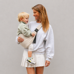 Woman carrying her toddler in the NAEVII Toddler Sling Carrier in beige, front carry with padded shoulder strap#Color_Beige