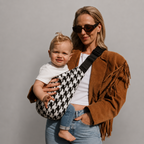 Woman in sunglasses carrying her toddler in the NAEVII Toddler Sling Carrier, black and white Houndstooth, front carry#Color_Houndstooth