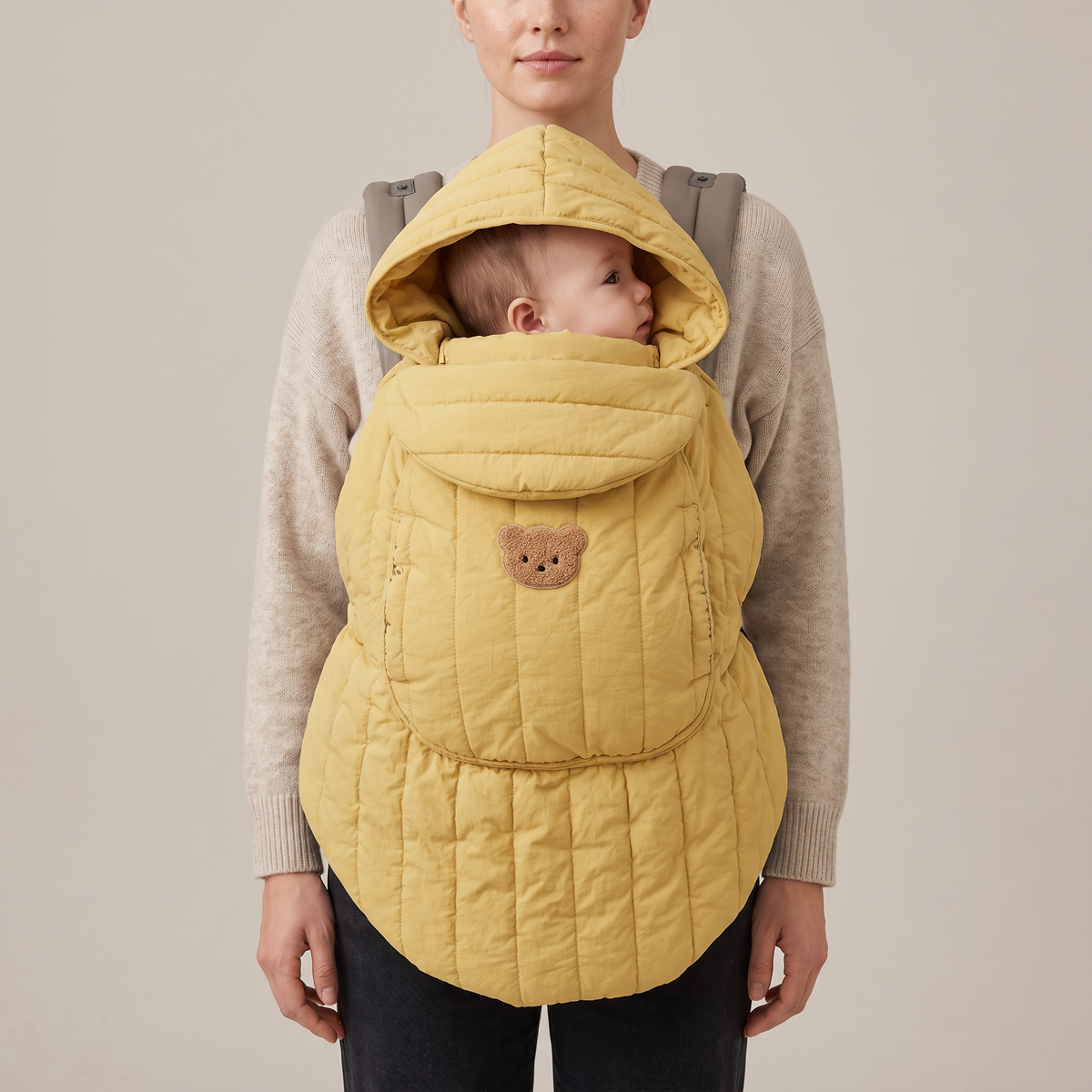 Mother wearing the butter quilted babywearing cover over her carrier — Orla Babywearing Cover — NAEVII#Color_Butter